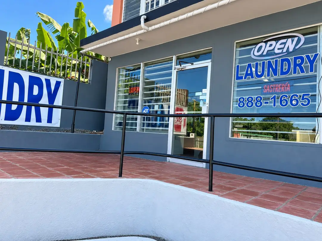 Laundry entrance with the open, laundry and tailoring sign, and the phone number 888-1665