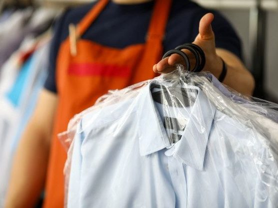 Staff member handing clean shirts to a customer: pickup and delivery in Río Grande